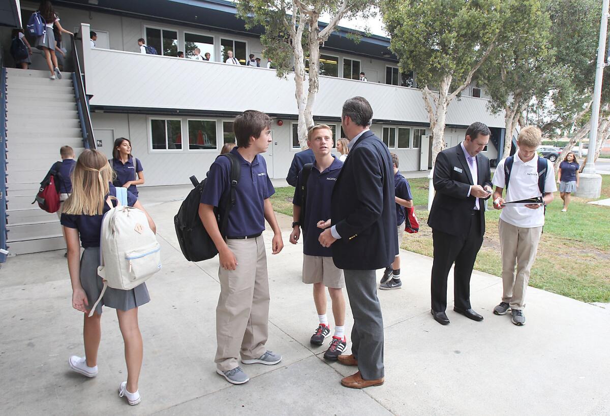 Head of School David O'Neil, middle, and language teacher Mike Arldt, far right, help kids navigate on the first day and year at Pacifica Christian High School in Newport Beach on Tuesday. Students are in grades 9 and 10 this year on the first day of school.