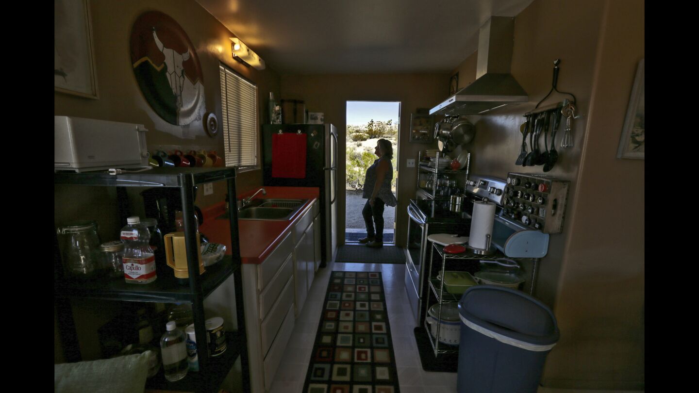 Anne Krieghoff stands in the door of the kitchen at her vacation home in Yucca Valley.