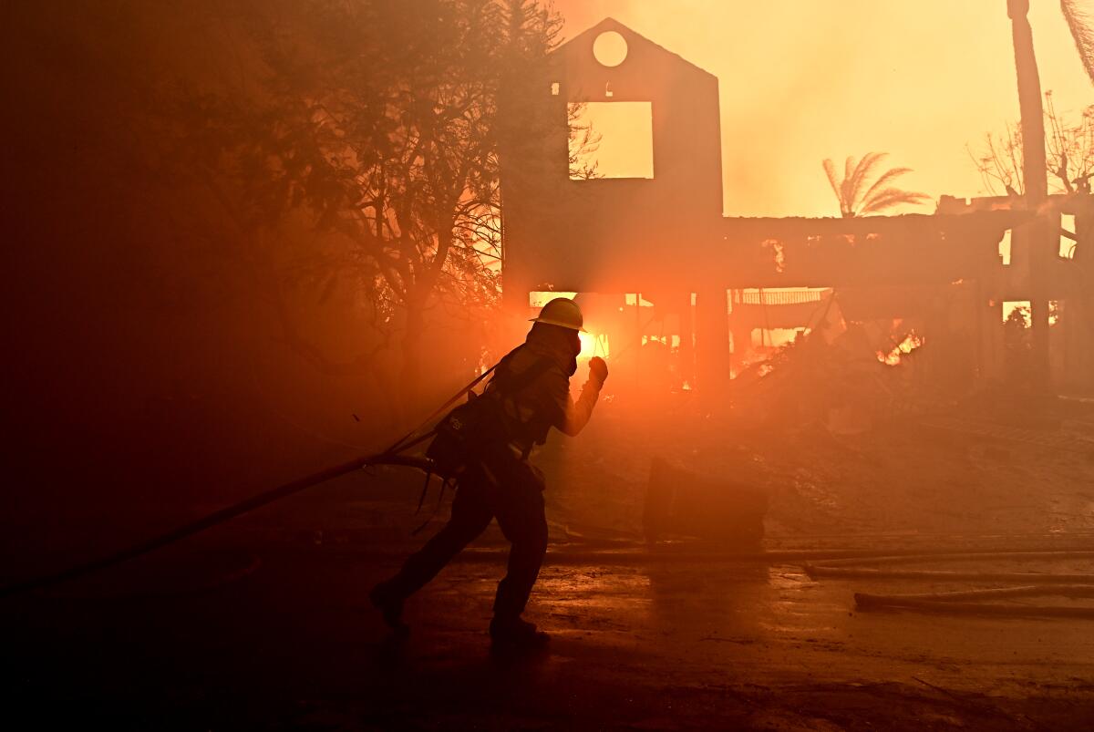 A firefighter hoses down a home