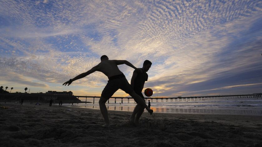 Visitors from Italy play a game of score on the sand near the Ocean Beach Pier just before sunset.