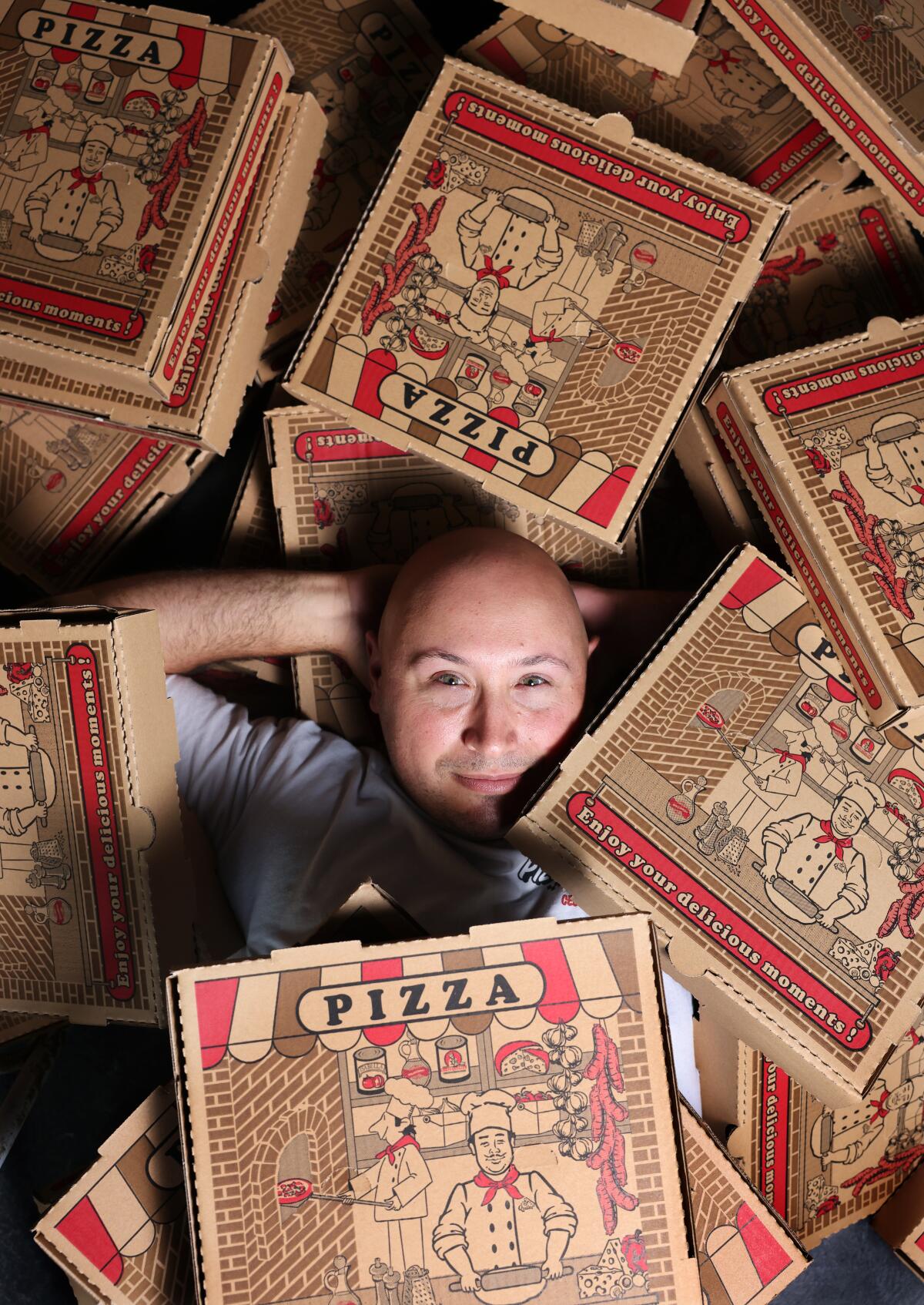 Pizza of Venice co-owner Jamie Woolner at his Altadena restaurant, surrounded by pizza boxes