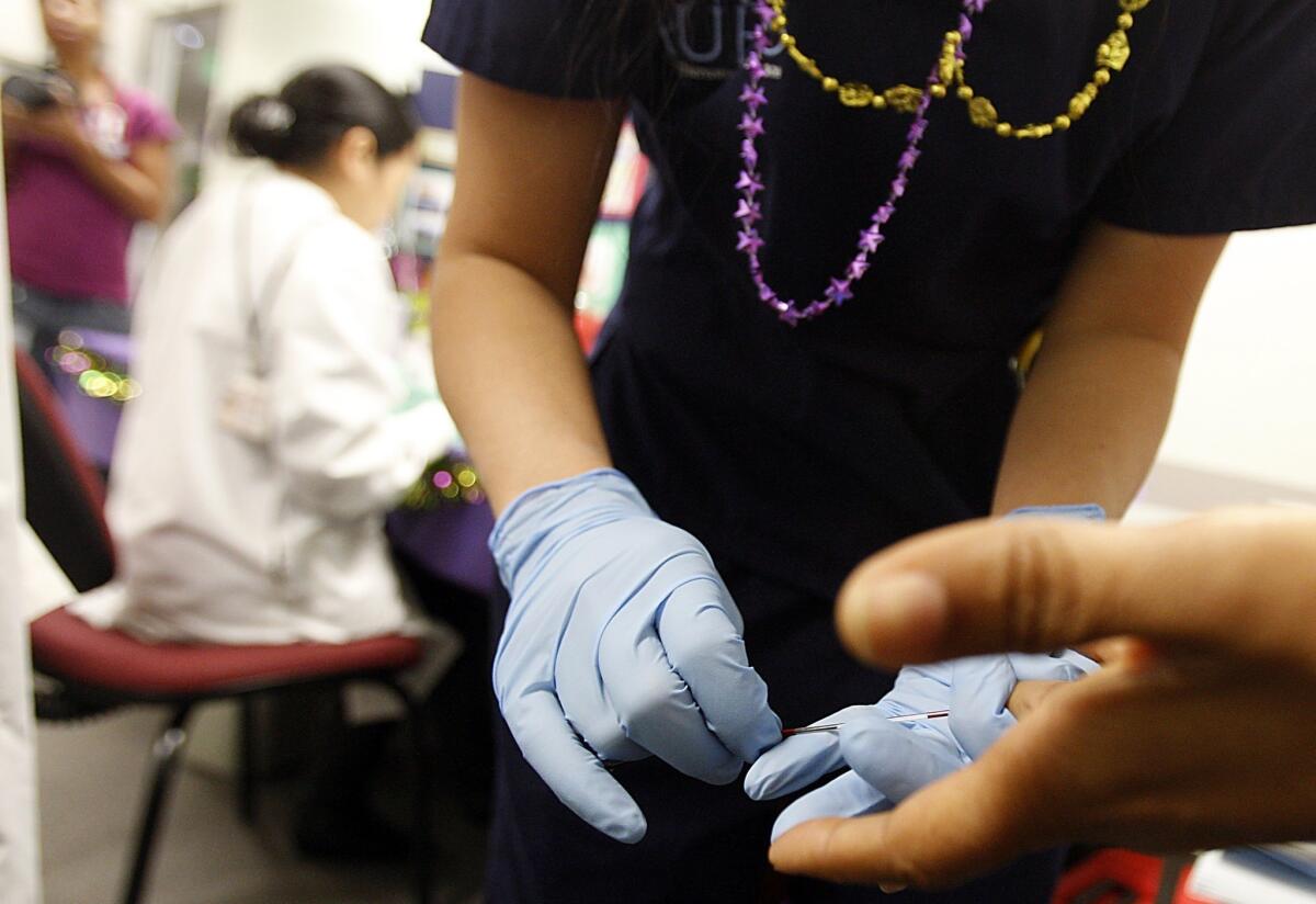 A nursing student takes a blood simple during a free health screening event in Long Beach in February. A federal panel now recommends that everyone ages 15 to 65 be screened for HIV, the virus that causes AIDS, and not just people in high-risk groups.