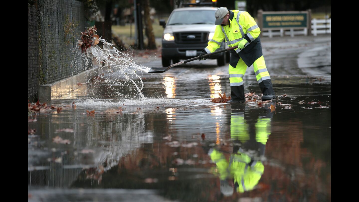 San Dimas Public Works Supervisor Terry Gregory cleears a clogged drain from North San Dimas Canyon Road as heavy rains cause clogged drains and mud flows in San Dimas, Glendora and Azusa.