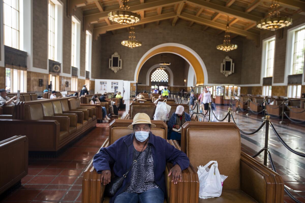A woman sitting inside Union Station wears a mask.
