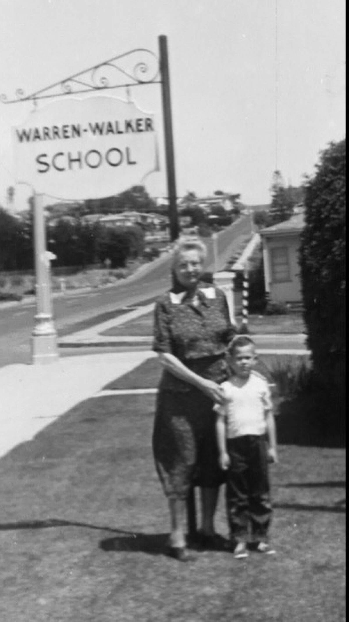 Nellie Warren-Walker poses with one of her students beneath the Warren-Walker School sign at 4605 Point Loma Ave.