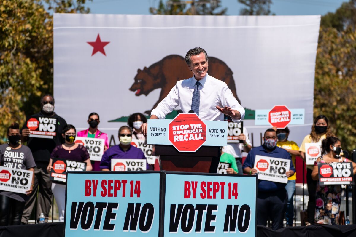 Gov. Gavin Newsom amid signs that read "by Sept. 14: vote no."