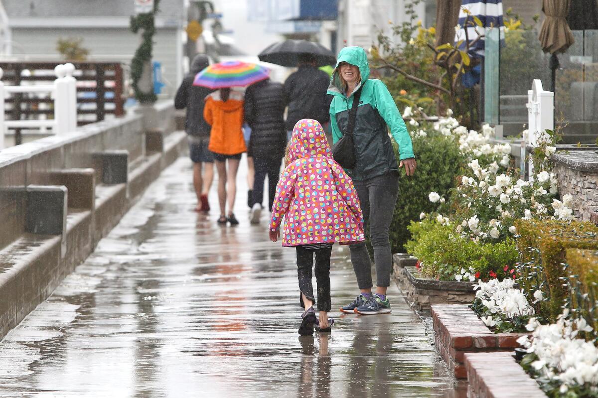 People walk around Balboa Island in Newport Beach during Wednesday's rain.