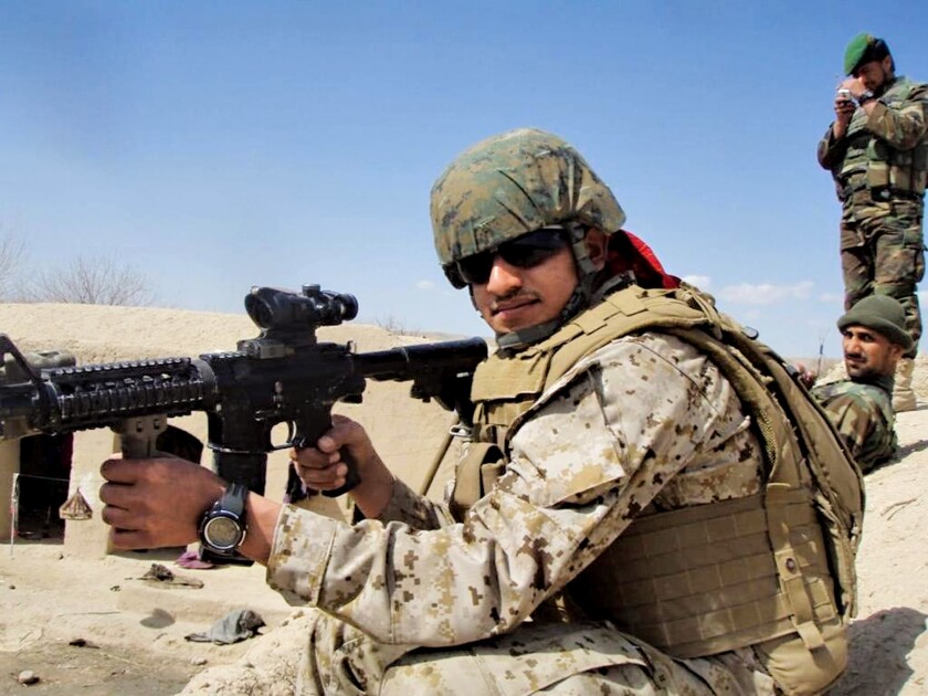 Zainullah Zaki in a military uniform and holding a rifle near some soldiers.