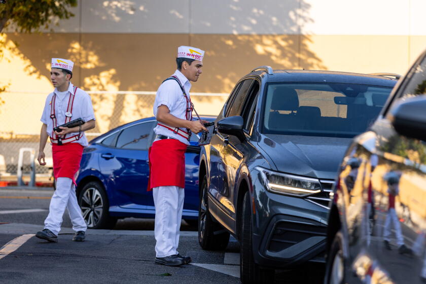 Los Angeles, CA - July 13, 2026 : A drive-thru worker works the long lines at the In-N-Out Burger at 9245 Venice Blvd. on Monday, July 13, 2026 in Los Angeles, CA. (Jason Armond / Los Angeles Times)