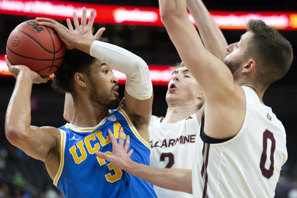 UCLA guard Johnny Juzang looks to pass while Bellarmine guard Alec Pfriem and forward Ethan Claycomb.
