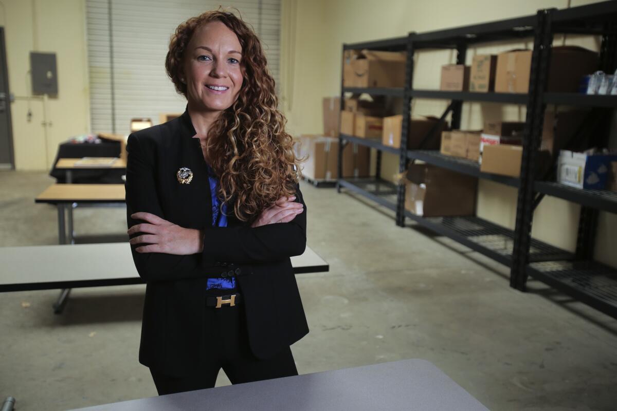 Jodie Grenier, standing with arms crossed and smiling at the camera, inside a warehouse in Vista