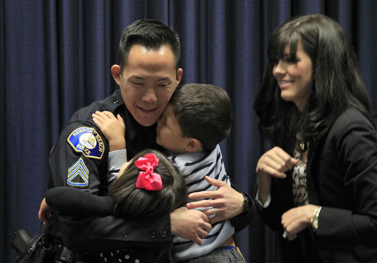Sgt. Darrin Joe shares a hug with his son Scott, 4, and daughter Whitney, 2, after his wife Wendy, right, pinned his new badge on him during a promotions ceremony at the Newport Beach Police Department on Thursday. (Kevin Chang/ Daily Pilot)