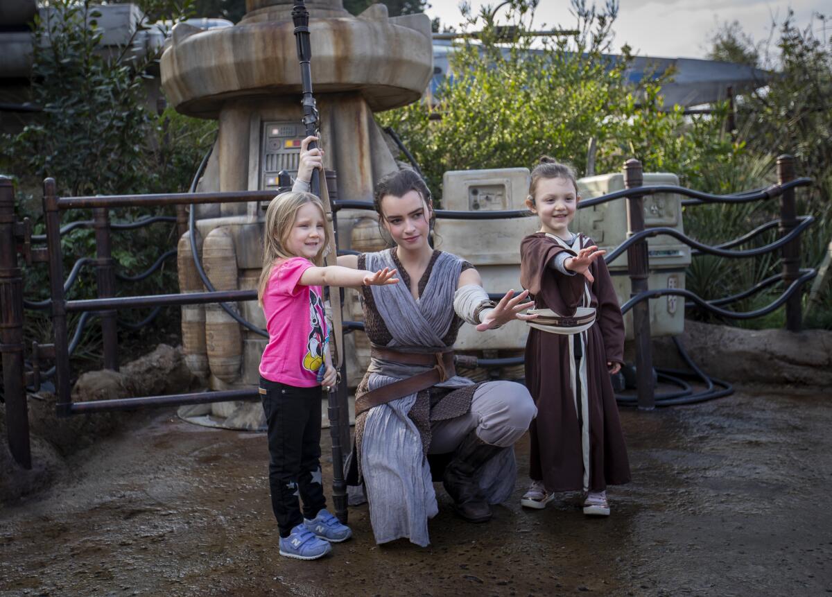 A cast member dressed as Rey poses for a photo with Penny, left, and Adelaide Remaklus of Ferndale, Wash., at Disneyland. 
