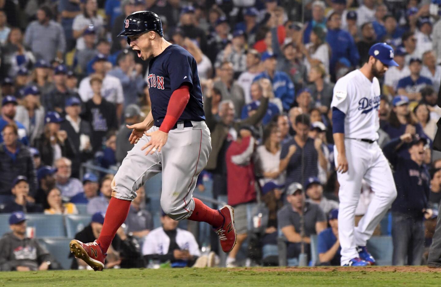 Red Sox base runner Brock Holt celebrates the go-ahead run in the 9th inning as Dodger reliever Dylan Floro walks back to the mound in the 9th inning.