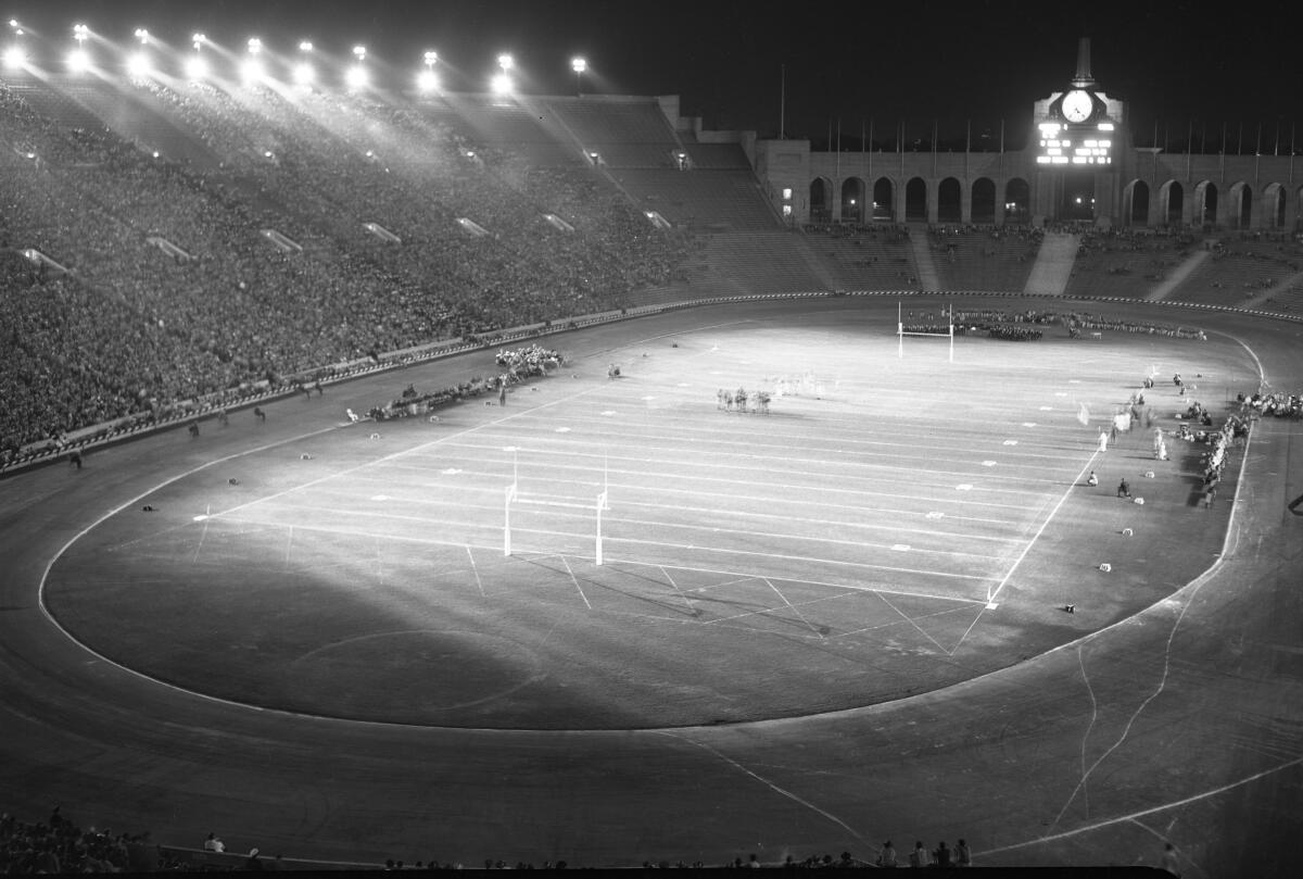 A football stadium under a bank of lights.