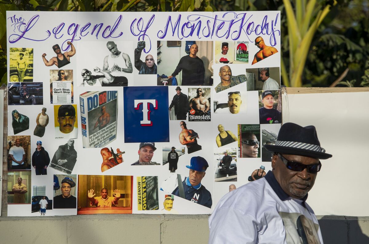 Mad Bone stands near a poster remembrance at a vigil for Kody Scott, a former L.A. Crips gang member, in South Los Angeles.