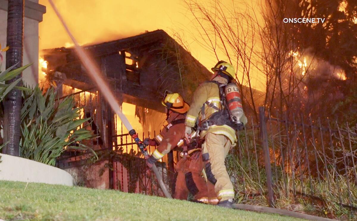 Firefighters use a hose to spray water onto a burning building