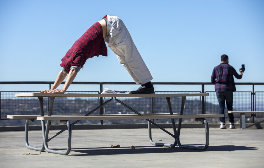 A man does a yoga pose on a picnic table outside the Griffith Park Observatory.