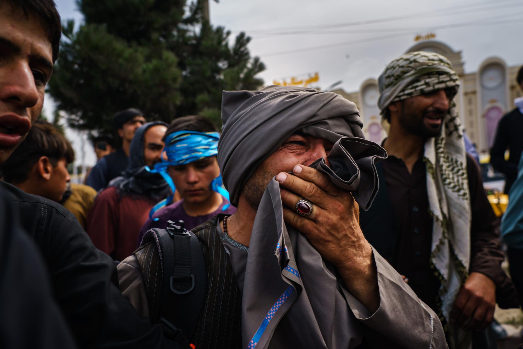 A group of men, one of them weeping