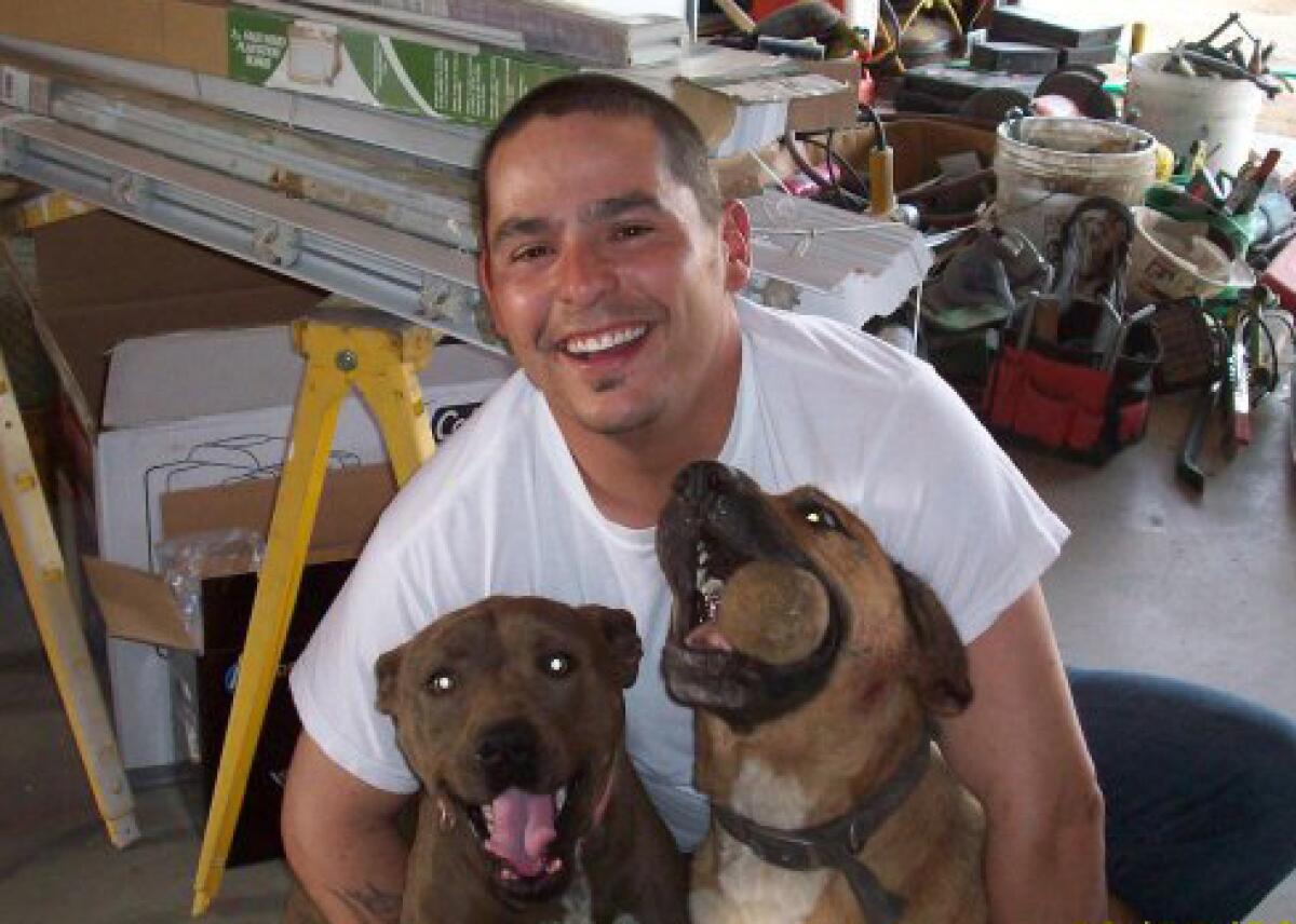 Tony Garza smiles as he poses for a photo with two dogs.
