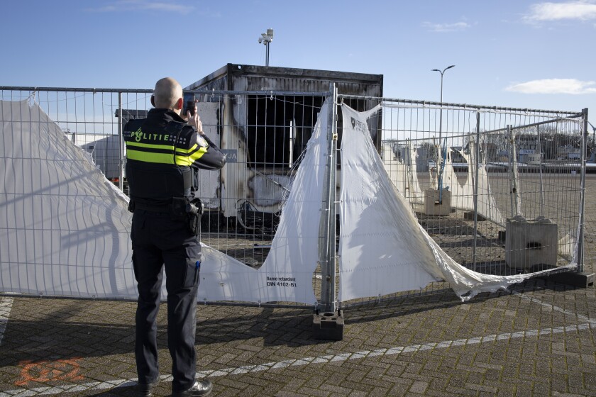 FILE - In this Jan. 24, 2021, file photo, a police officer takes pictures of a burned-out coronavirus testing facility in the fishing village of Urk in the Netherlands after it was set on fire the night before by rioting youths protesting on the first night of a nationwide curfew. A new report by the Geneva-based Insecurity Insight and the University of California, Berkeley’s Human Rights Center identified hundreds of attacks linked to fear or frustration around the coronavirus against health care workers and facilities in the past year. (AP Photo/Peter Dejong, File)