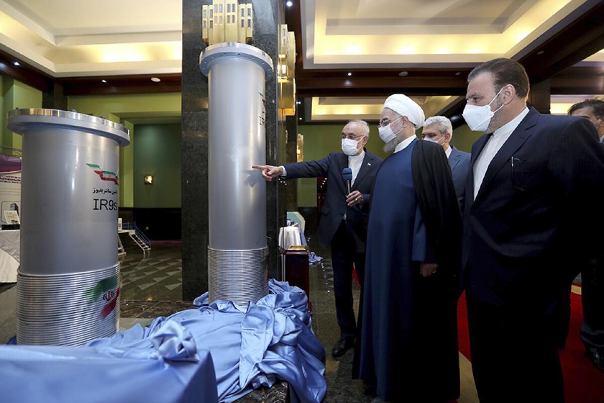 Iranian President Hassan Rouhani is shown some pipes and other equipment by another man.