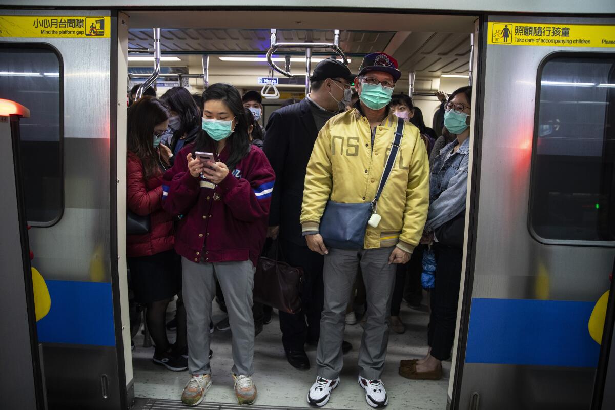 Commuters wearing masks pack a subway train in Taipei, Taiwan