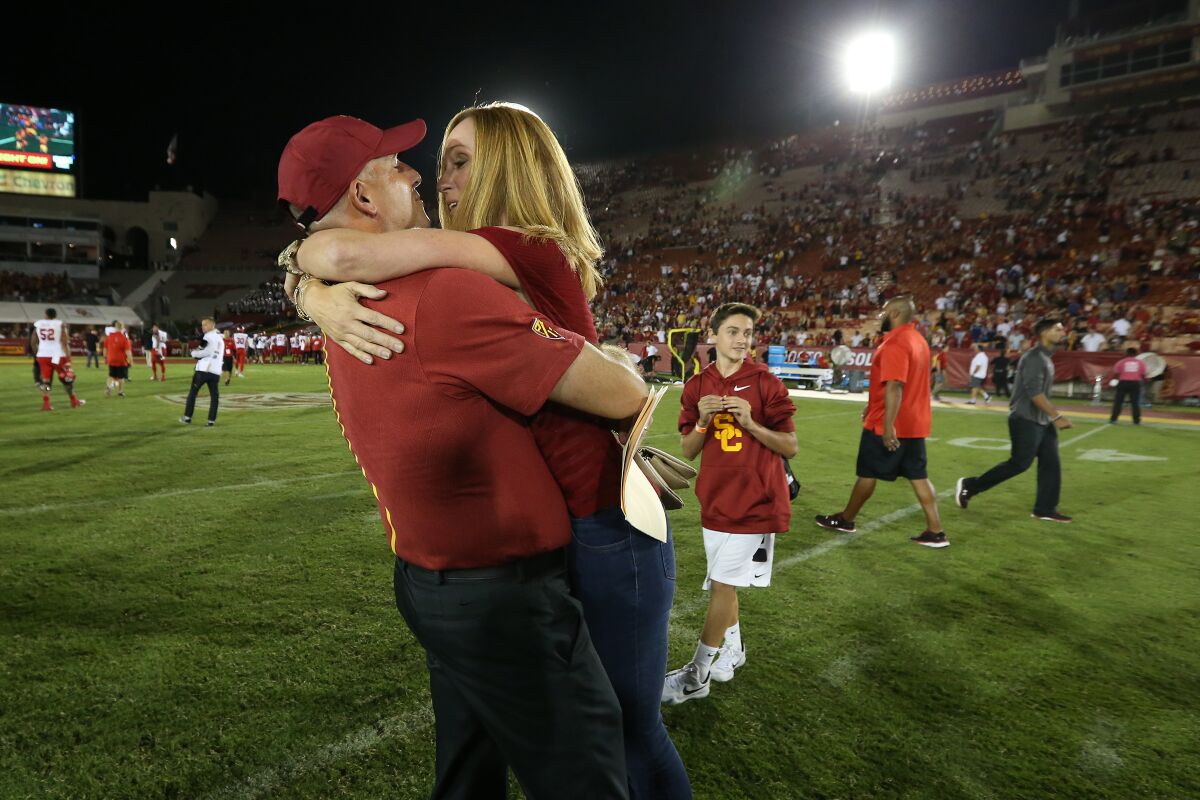 Then-interim USC coach Clay Helton is embraced by his wife, Angela, at midfield 