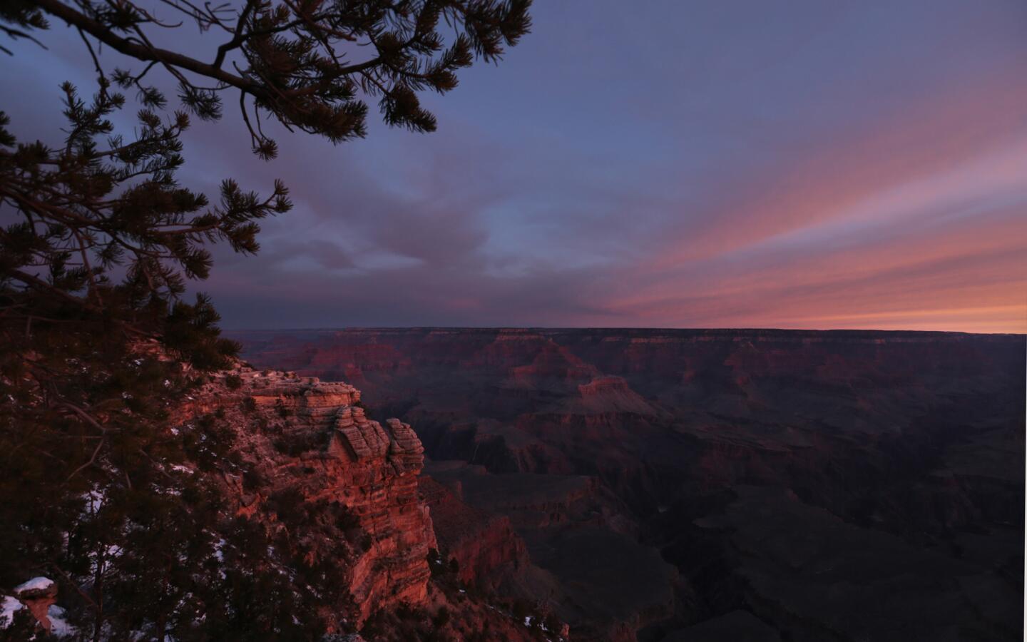 Dawn begins to illuminate the age-old rock formations of the Grand Canyon along the South Rim near Mather Point.