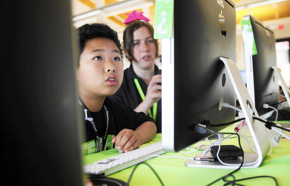 Kenny Feng, with the help of Katherine Gaul, a camp counselor, works on a computer during the iD Tech Camp at UC Irvine in 2011.