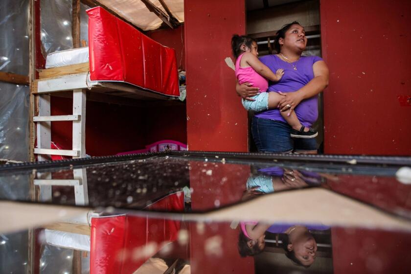 IMMOKALEE, FLA. -- MONDAY, SEPTEMBER 11, 2017: Petrona Nunez holds her child, Jazabell Nunez, 2 and surveys the damage caused by Hurricane Irma, to their home in Immokalee, Fla., on Sept. 11, 2017. (Marcus Yam / Los Angeles Times)