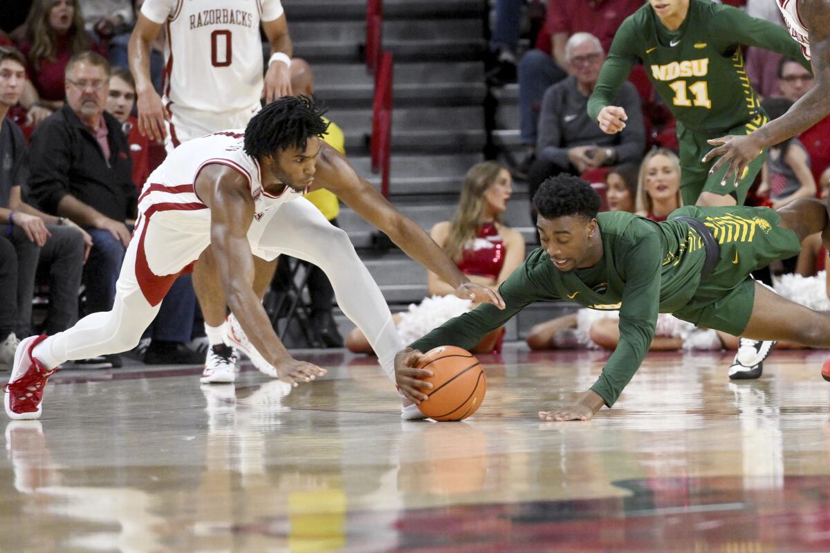 Arkansas guard Ricky Council IV, left, and North Dakota State guard Tajavis Miller, right, dive after the ball during the first half of an NCAA college basketball game Monday, Nov. 7, 2022, in Fayetteville, Ark. (AP Photo/Michael Woods)