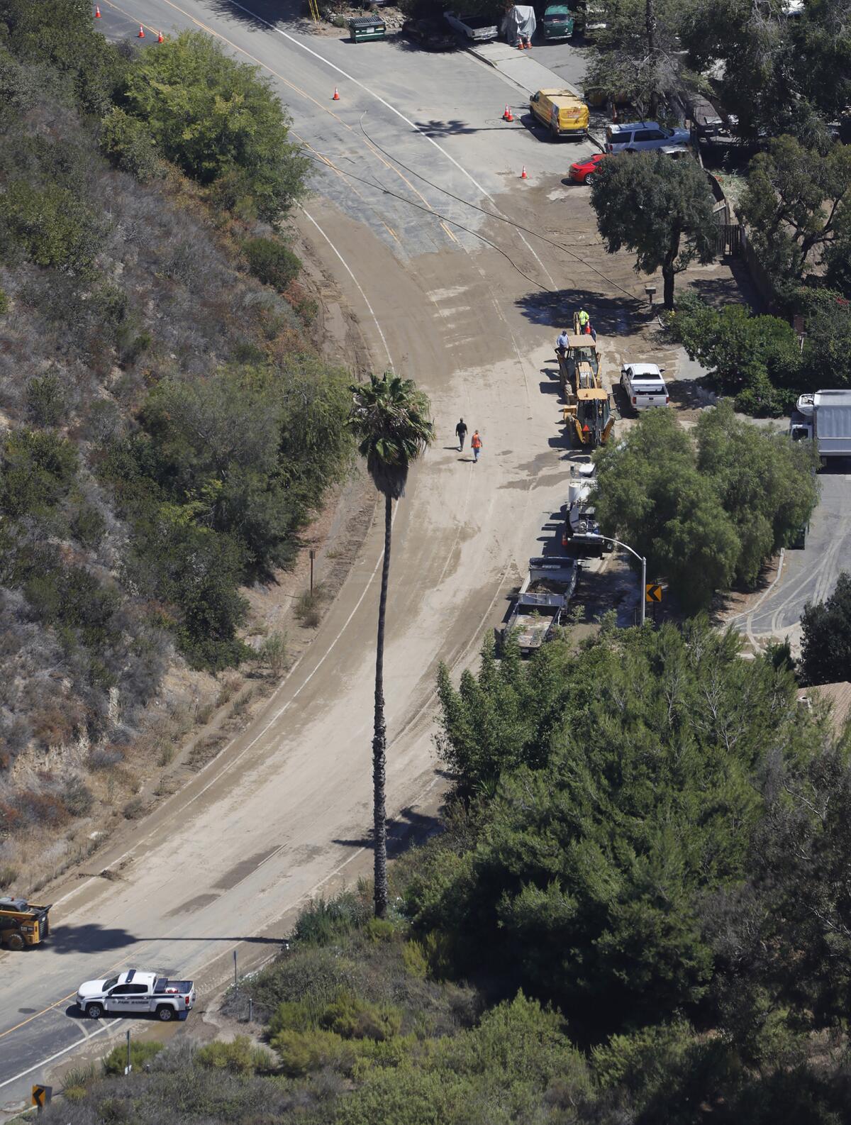 Laguna Beach Water District crews clear dirt and debris at the big bend in Laguna Canyon Road after a water main break.