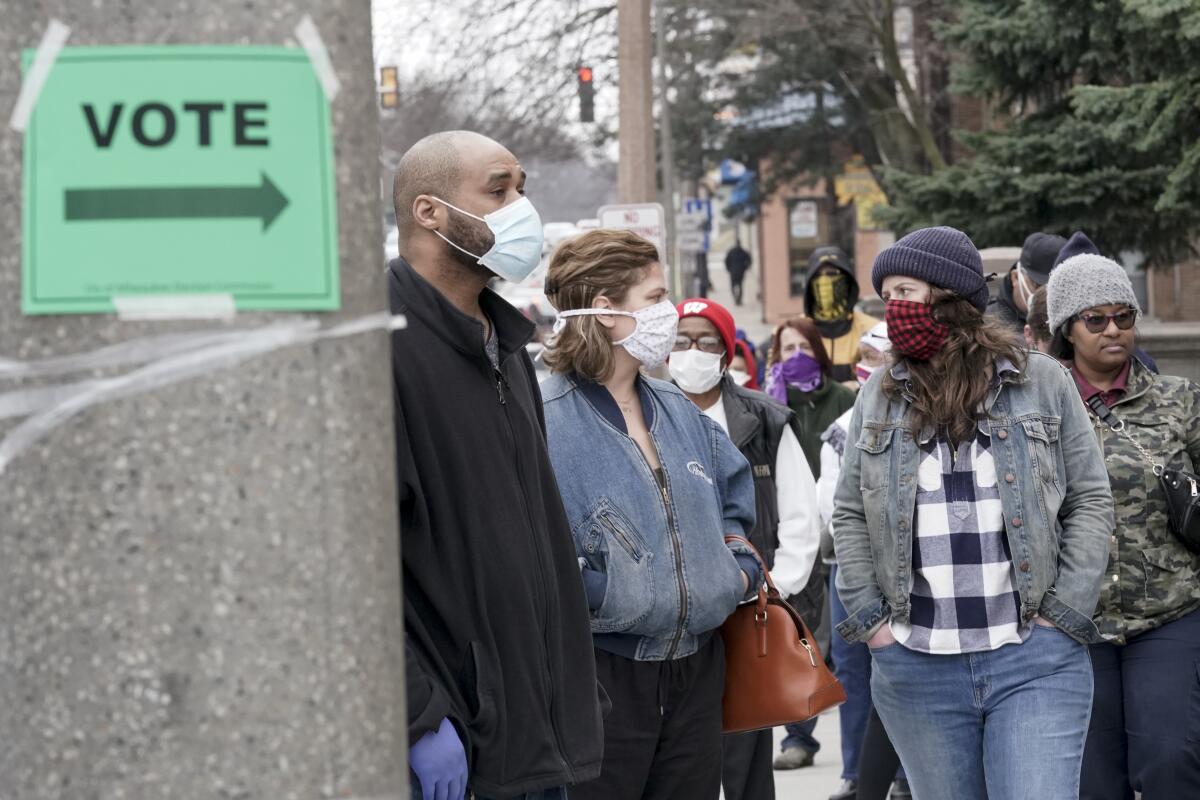 People in masks wait in line