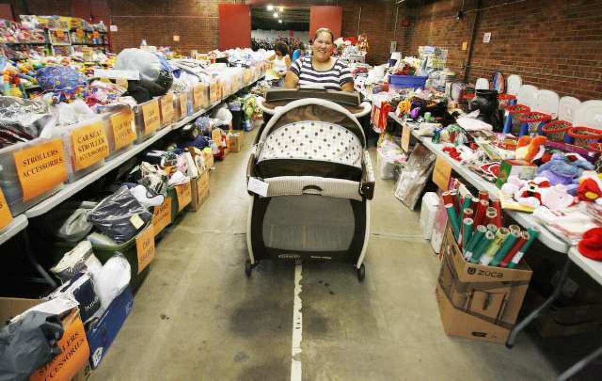 Elizabeth Barajas, of Van Nuys, rolls a portable crib to the checkout counter at the LA Kids Consignment sale in Burbank on Tuesday, where 625 consignors contributed 95,000 children's toys, clothes, games, strollers and a lot more.