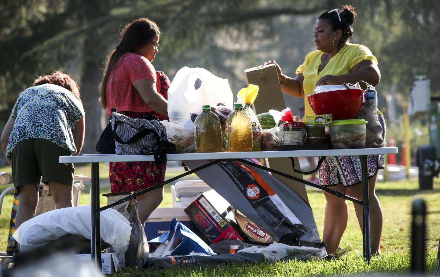 Cindy Esparza, second from left, and Elsa Elias set up a Fourth of July picnic after arriving at the Rose Bowl in Pasadena, where, come evening, there will be fireworks, music and more.