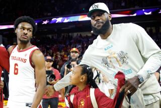 Lakers' LeBron James, right, pats the back of USC Trojans guard Bronny James (6) before the game