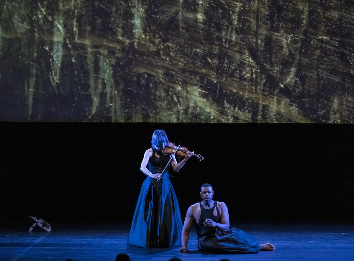 Violinist Jennifer Koh and baritone Davóne Tines perform with an abstract projection in the background.