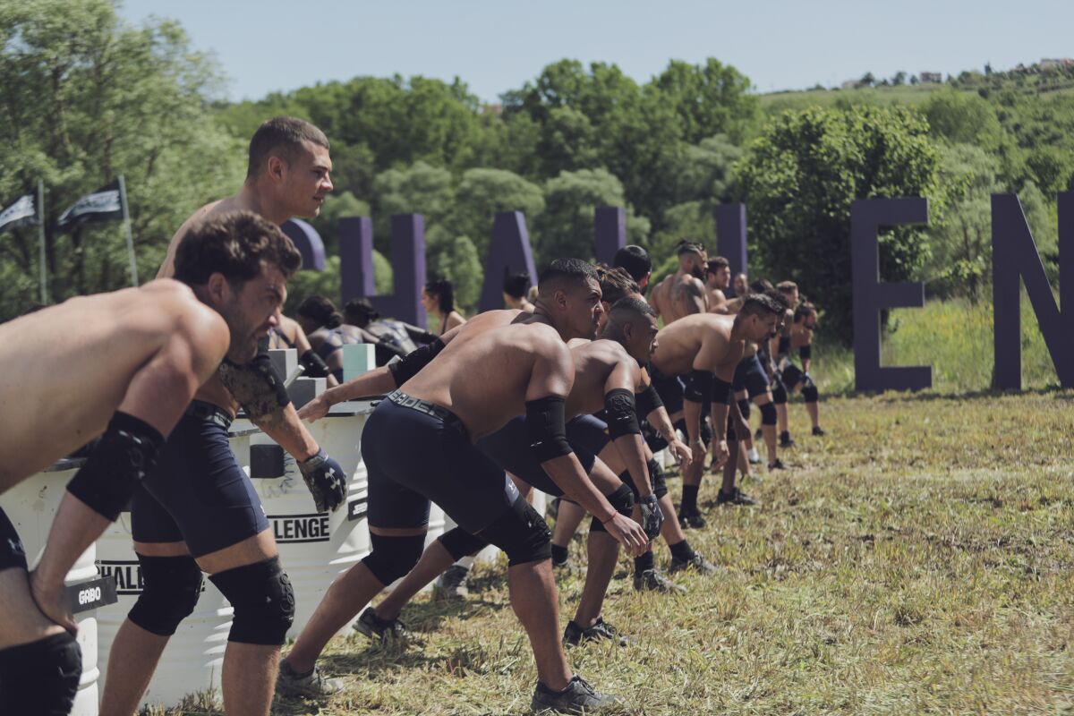 A line of men in matching black athletic shorts and knee pads preparing to start a race 
