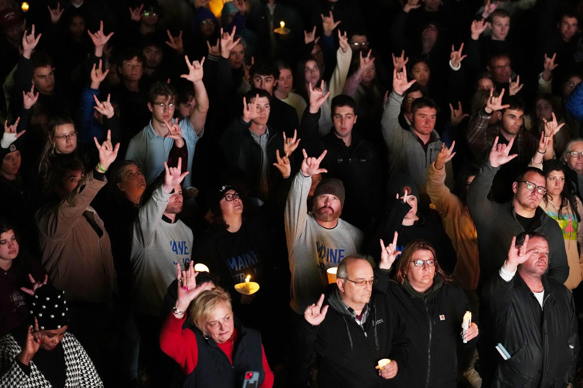 People raise their hands with outer fingers and thumbs extended, the sign for "I love you"
