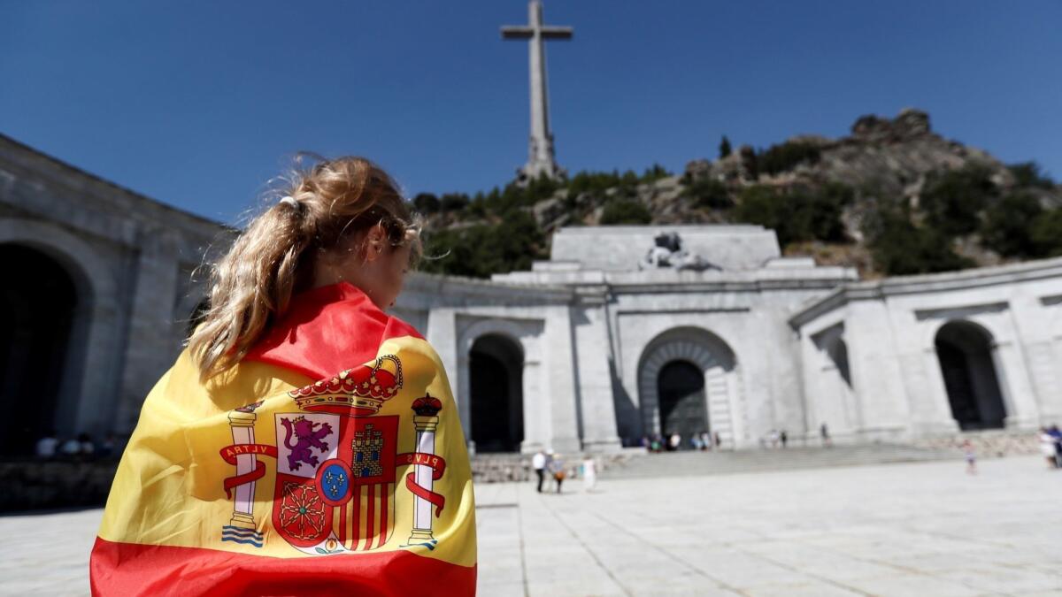 A woman wears the Spanish flag like a cape at the Valley of the Fallen memorial in San Lorenzo del Escorial.