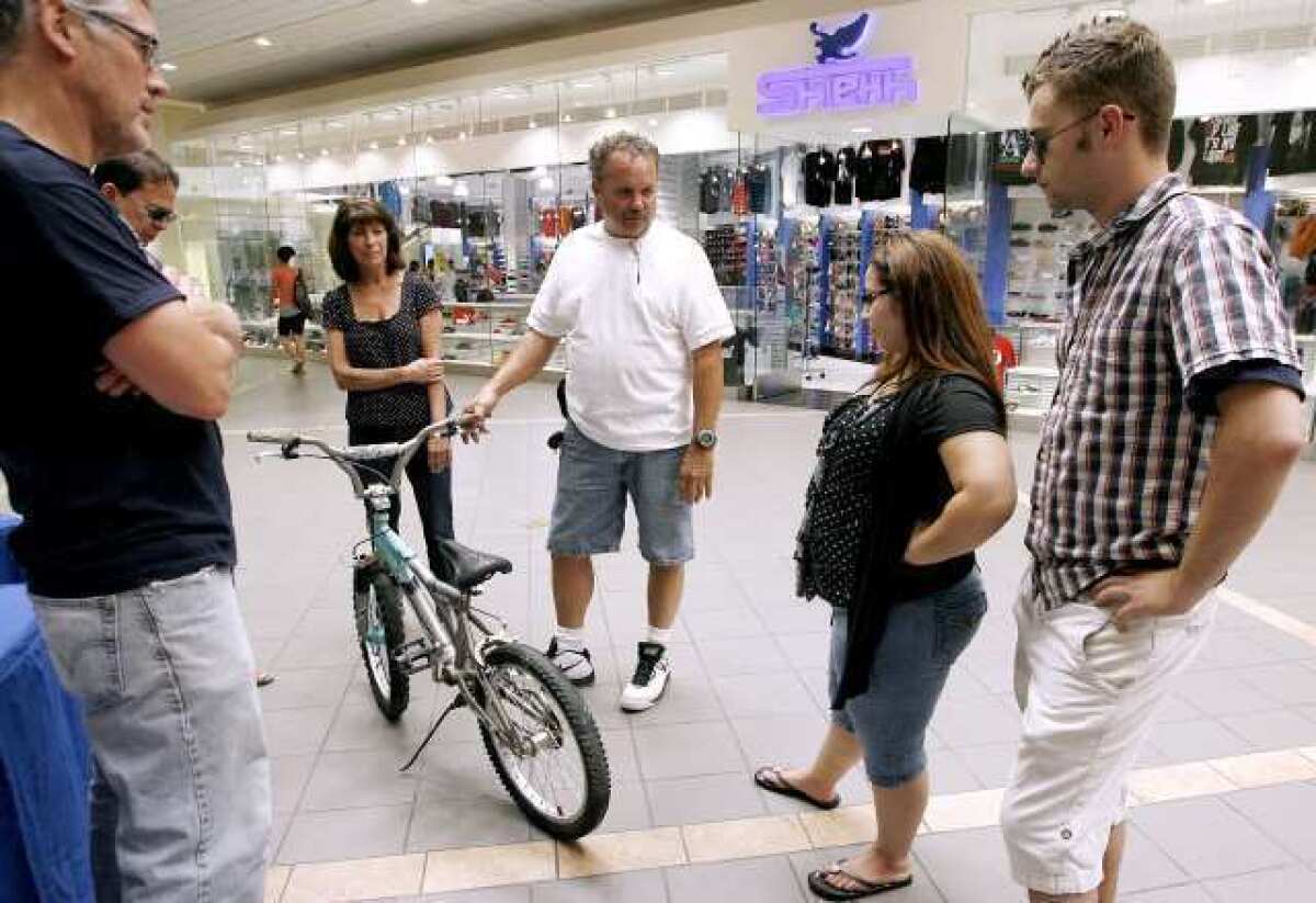 Bike Angels member Rob Wendlandt, center, holds a used bike that Crystal Girone, second from right, and Michael Cozakos, right, donated to the group at the Burbank Town Center. The group hopes to collect about 200 bikes, refurbish them and give them away for Christmas. The group will clean the bikes and replace at least the tires, seat, handles and anything else that needs repair.