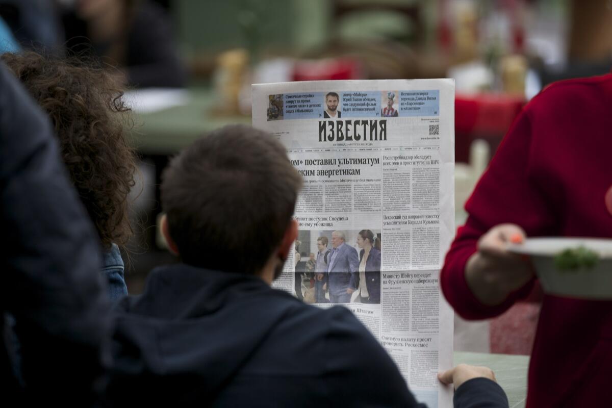 A street cafe visitor reads the Russian newspaper Izvestia with a front-page story about former National Security Agency contractor Edward Snowden.