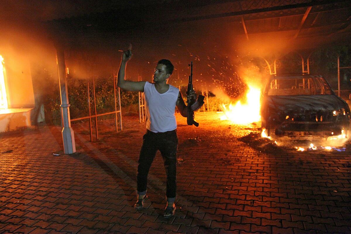 An armed man gestures as buildings and cars are engulfed in flames inside the U.S. consulate compound in Benghazi, Libya. Warning: The next photo in this gallery contains an image that may be disturbing to some readers.