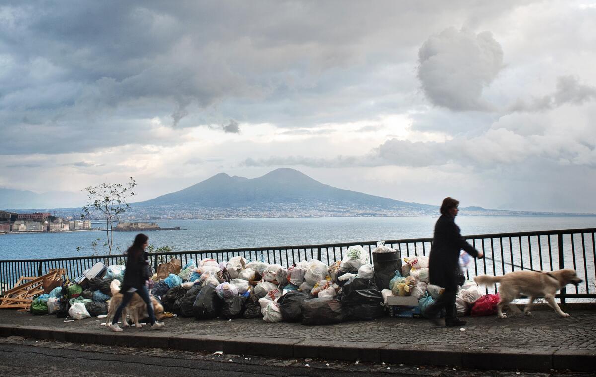 People walk past uncollected trash in Naples, Italy.