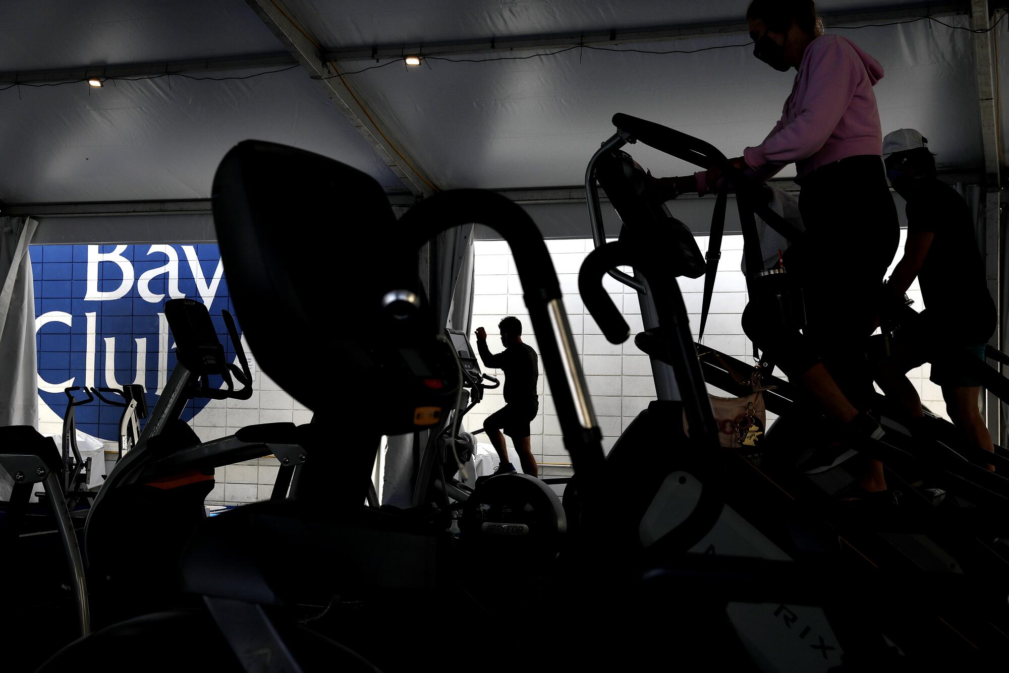 People are seen in silhouette on stairclimbers.