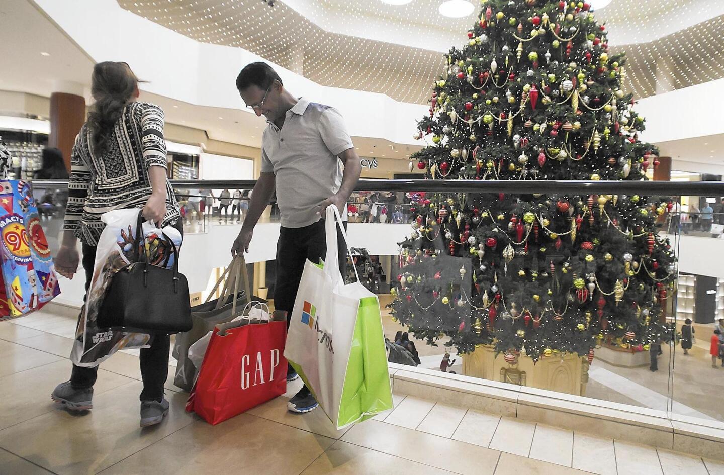 Shoppers carrying bags from various stores take a break while shopping during Black Friday at South Coast Plaza in Costa Mesa.