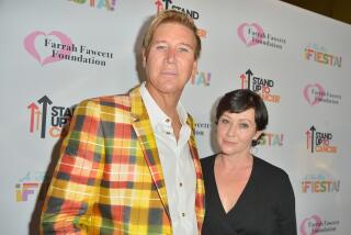 Dr. Lawrence Piro wears a a bright plaid blazer while posing next to actor Shanen Doherty who is wearing a black v-neck