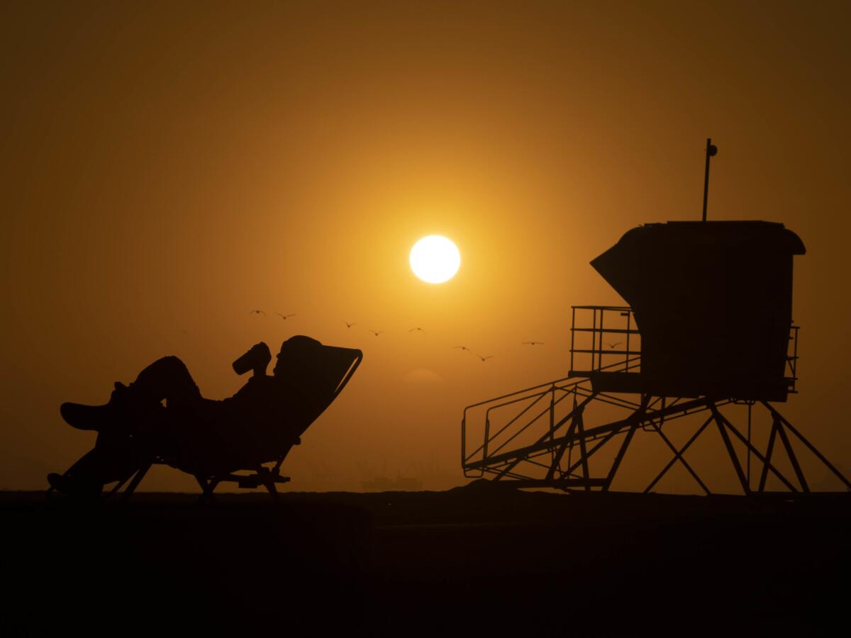 A camper relaxes in a beach chair at sunset in Huntington Beach.