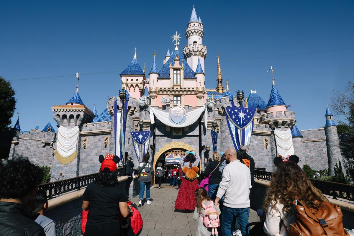 People walk up a ramp to a theme park castle.